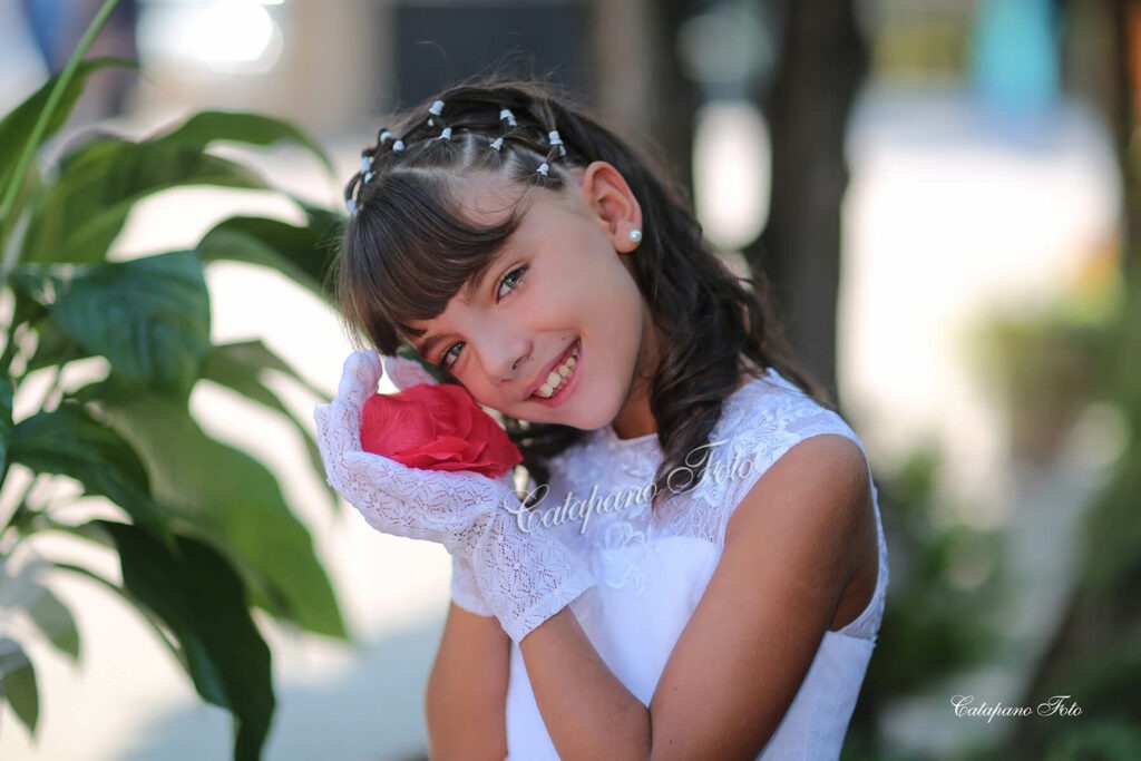 bambina prima comunione in posa con un fiore