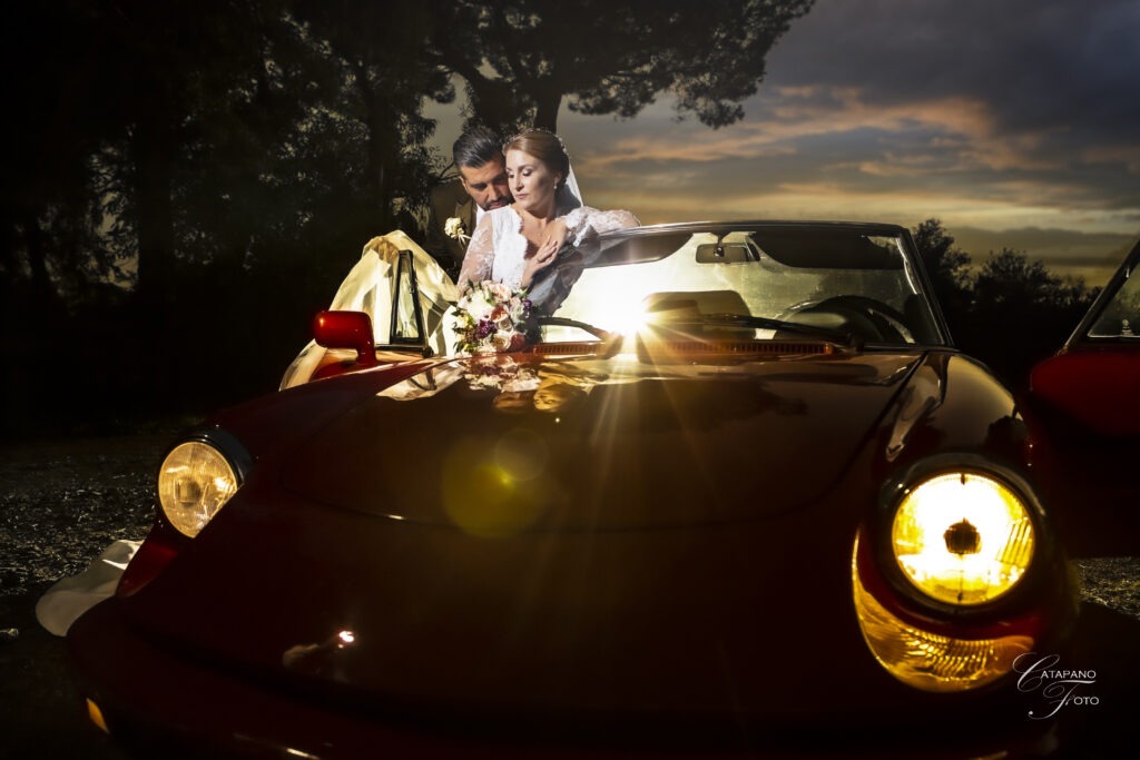 fotografia di un'emozione senza tempo dove gli sposi si abbracciano vicino alla loro auto